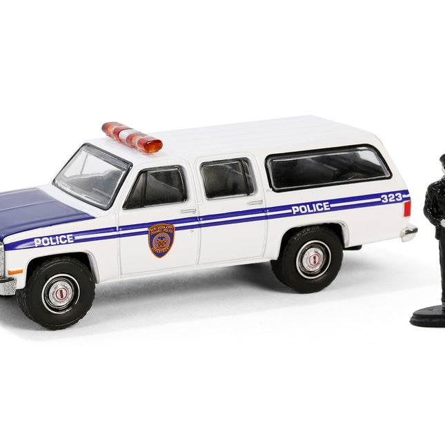 1985 GMC Suburban 2500 "New York City Transit Police Department" White with Blue Stripes and Police Officer Figure "The Hobby Shop" Series 16 1/64 Diecast Model Car by Greenlight